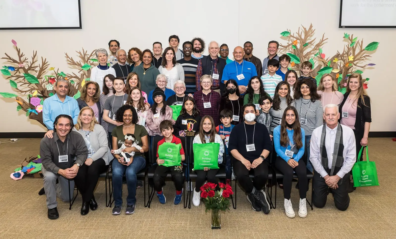 A large group gathered in front of a painted tree at a community conference