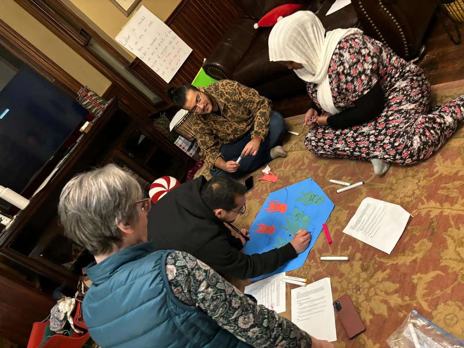 Participants at a youth institute camp working together on drawings spread across the floor