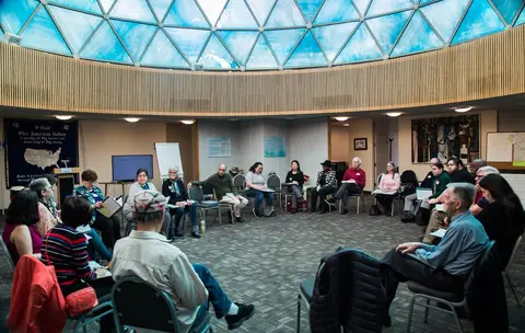 Friends seated in a wide circle beneath a glass dome
