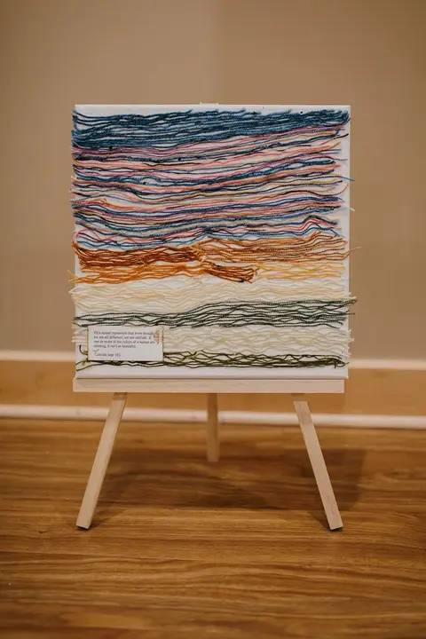 A woven textile with bands of color displayed on an easel
